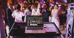 DJ performing at an indoor event with guests dancing in the background.