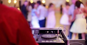 DJ performing at an indoor event while guests dance and enjoy the music.